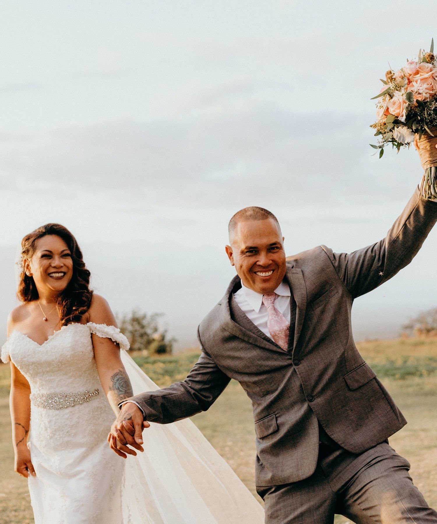 Сouple wearing a white gown and a gray suit. Mobile image